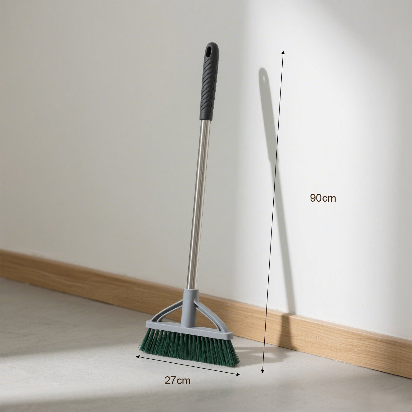 緑のほうきで床を掃除する様子